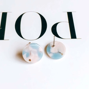 Macro view of round resin earrings featuring blue and pink marble texture with steel pins