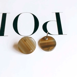 Macro shot of circular acetate earrings with amber marble texture and silver metal pins