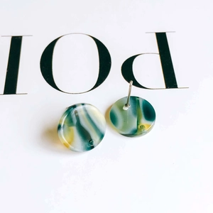 Detailed macro view of round marble texture acetate earrings with secure metal pins