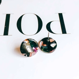 Macro shot of circular resin earrings with multicolor marble texture and silver metal pins