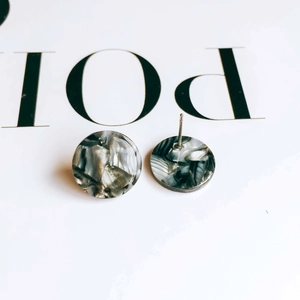 Macro view of marbled acetic acid resin round stud earrings with steel pins