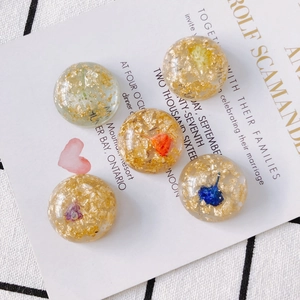 Détail de 5 cabochons en résine avec fleurs séchées et accents de feuilles d'or