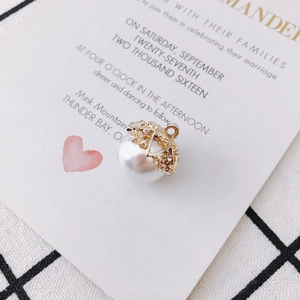 Detailed view of heart-patterned gold metal cap with rhinestones on a white pearl pendant