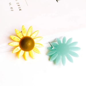 Pendientes minimalistas de girasol y margarita sobre un fondo blanco elegante