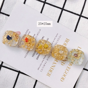 Détail de breloques carrées en résine 25mm avec flocons d'or et fleurs séchées colorées