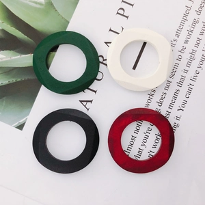Flat lay of colorful geometric wooden ring charms in dark green, ivory, black, and reddish brown