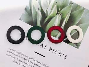 Detailed view of matte geometric wooden rings in black, green, red and cream colors