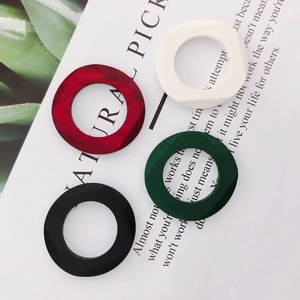 Macro detail of geometric wooden earring charms in red, white, dark green, and black
