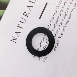 Macro detail of a black wooden geometric ring pendant with textured surface and faceted edges
