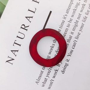 Close-up of a red geometric wooden ring pendant with natural grain on a minimal white card