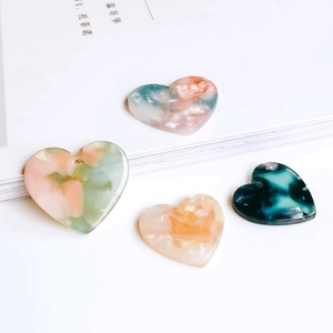 Detailed macro view of colorful marble patterned acetate heart charms for DIY jewelry making