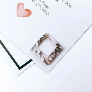 Macro-detail van vierkante acetaat hangers met grijze marmeren textuur voor DIY sieraden