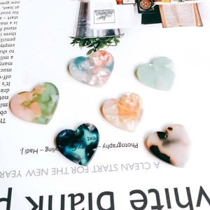 Macro detail of heart-shaped acetate charms in various marble colors for DIY jewelry making