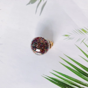 DIY transparent glass ball pendant with colorful sand and gold metal cap on marble