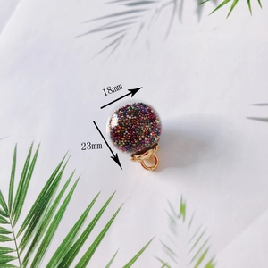Macro detail of 18mm glass ball pendant with colorful beads and golden metal hook