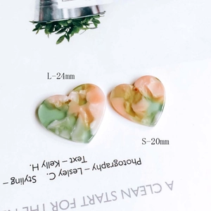 Macro shot of heart-shaped marble acetate pendants in peach pink and mint green colors