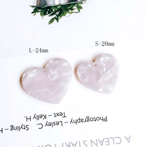 Close-up of heart-shaped marbled acrylic pendants in 24mm and 20mm sizes for DIY jewelry