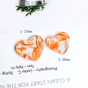 Detail view of heart-shaped marble acetate charms in 20mm and 24mm sizes