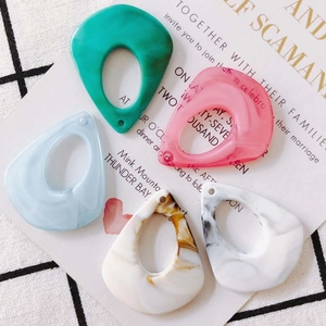 Macro view of five colorful teardrop resin charms in marble and solid finishes