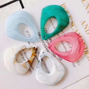 Detailed view of colorful teardrop acetate charms in five marble patterns with top holes