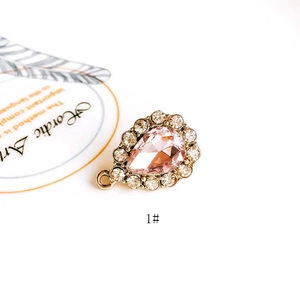 Detailed view of pink crystal teardrop pendant with gold metal base and rhinestones