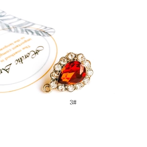 Detailed view of red teardrop gemstone pendant with white crystal halo and gold ring loop