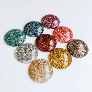 Détail de cabochons en résine ronds avec feuilles d'or et paillettes pour loisirs créatifs
