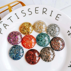 Détail macro de cabochons ronds en résine avec des flocons de feuilles d'or colorées sur plat