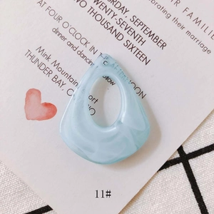 Macro detail of light blue resin drop earring with textured wavy surface on grid pattern