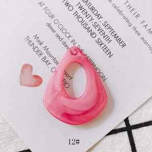 Close-up of pink translucent resin teardrop pendant with fluid texture for DIY jewelry