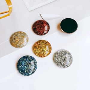 Détail de six charmes de support téléphone en résine avec feuilles d'or et paillettes