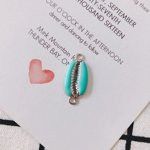 Detail of shell-shaped teal enamel charm with silver plating and double hanging rings