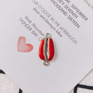 Detail of red shell-shaped enamel jewelry connector with dual rings for DIY making