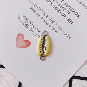 Detailed view of shell-shaped gold-plated jewelry connector with yellow enamel finish