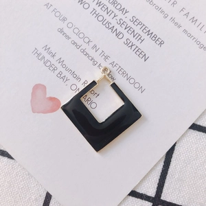Détail d'un pendentif d'oreille carré en or géométrique avec émail noir et blanc