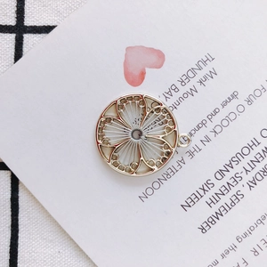 Macro shot of circular gold flower pendant with intricate white woven thread patterns