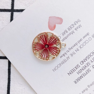 Detail of round golden floral pendant with red silk thread weaving for DIY jewelry making