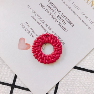 Macro detail of red hollow round woven texture DIY earring charm on wedding card