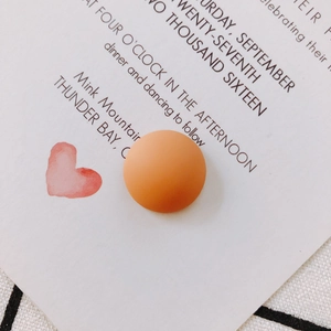 Close-up of a round matte orange resin bead on a decorative background for DIY crafts