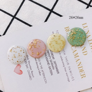 Macro view of 26mm round acrylic charms with gold foil flakes for DIY jewelry making