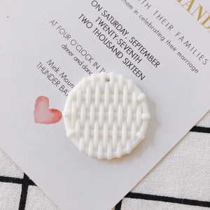 Detailed view of a white round resin pendant with intricate woven texture and small hole