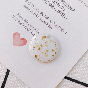 Detailed macro view of white resin round pendant with gold foil flakes for DIY jewelry