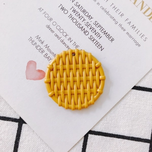 Detailed macro view of yellow round resin pendant with realistic woven vine texture pattern