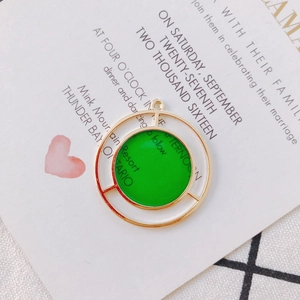 Detail of round geometric pendant with green enamel and gold plated circular frames