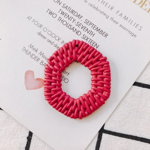 Dettaglio macro di pendenti tondi in resina rosa scuro con trama intrecciata effetto rattan
