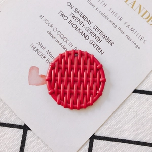 Macro detail of red circular resin charm with woven texture and single hanging hole