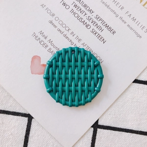 Macro shot of circular teal resin charm with woven texture and top hole for DIY jewelry
