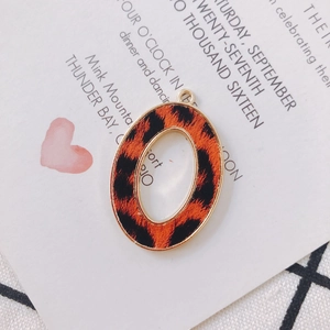 Macro detail of oval alloy pendant with golden edges and leopard print leather texture