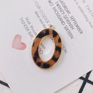 Detail of leopard print oval pendant with gold alloy frame on a minimalist backdrop