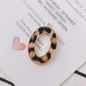 Macro detail of oval leopard print charm with gold metal frame for DIY jewelry making